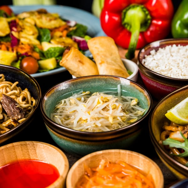 A vibrant spread of Indian dishes, including noodles, rice, spring rolls, and fresh vegetables.