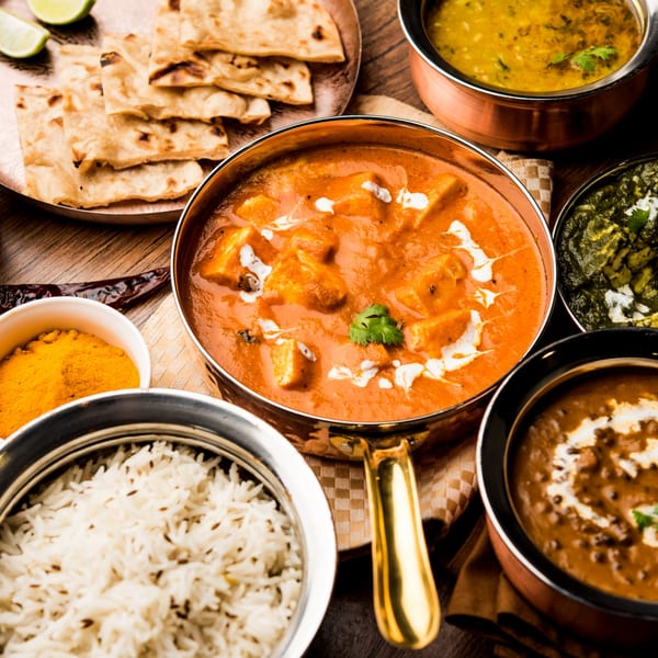 Assortment of Indian dishes including paneer butter masala, dal makhani, palak paneer, rice, and naan.
