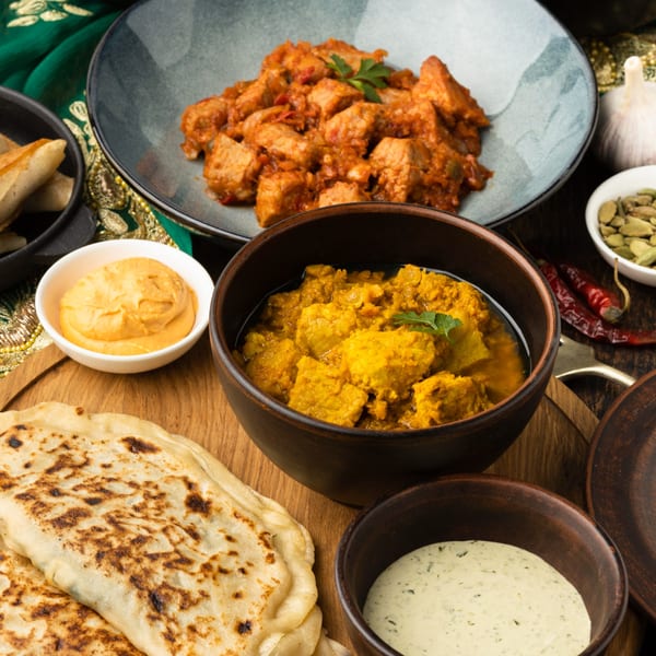Indian dishes including chicken tikka masala, paneer curry, naan bread, and various sauces and spices.